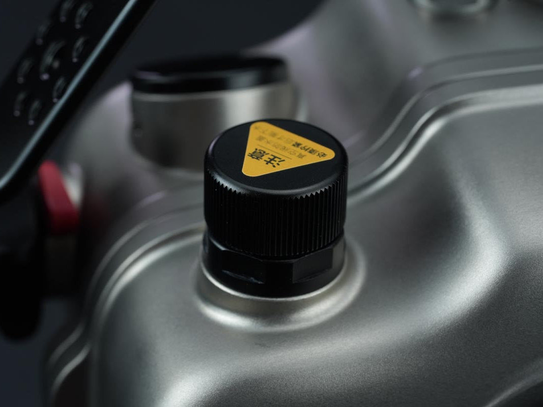 Close-up of a fuel tank cap with a yellow label on a vehicle.