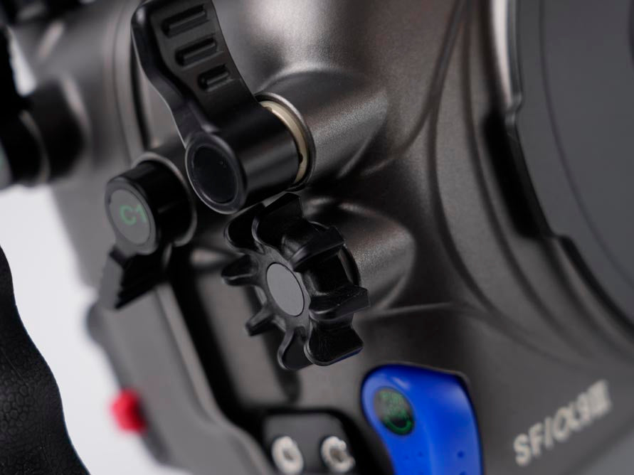 Close-up of a camera control panel with black dials, a blue button, and white 'SIFOCME' text on a dark gray body.