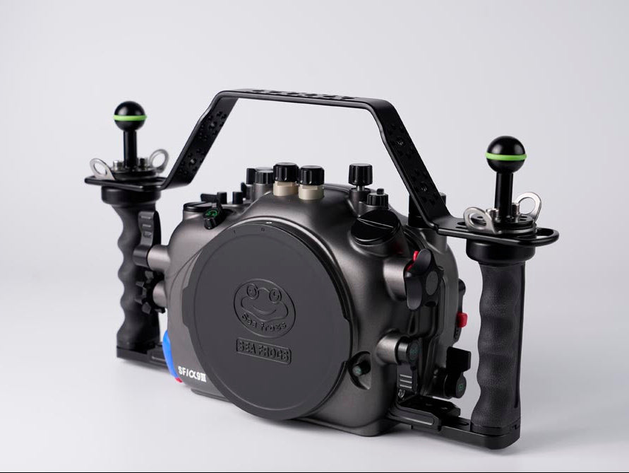 A black underwater camera housing with dual joystick controllers and a top handle, photographed on a light gray background. The housing features a circular front cover with a visible 'ROCKNROLLER' brand logo.