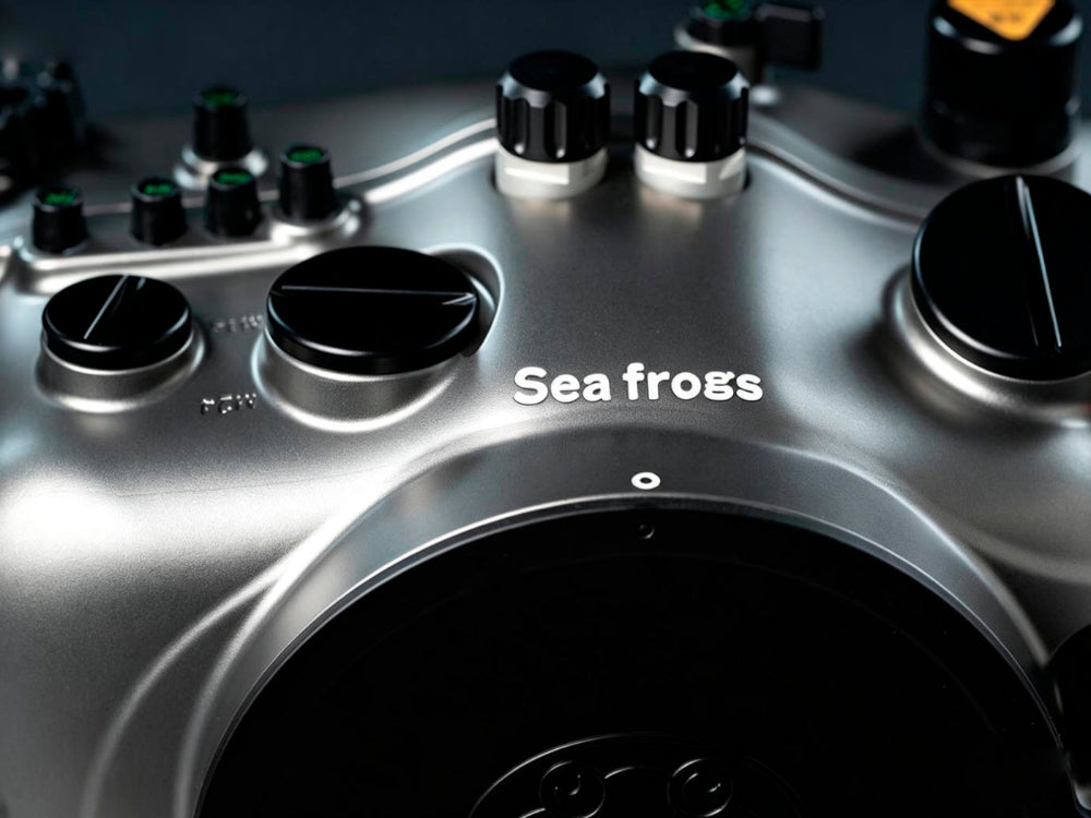Close-up of a metallic silver underwater camera housing with black control knobs and the white text 'Sea frogs' on the front.
