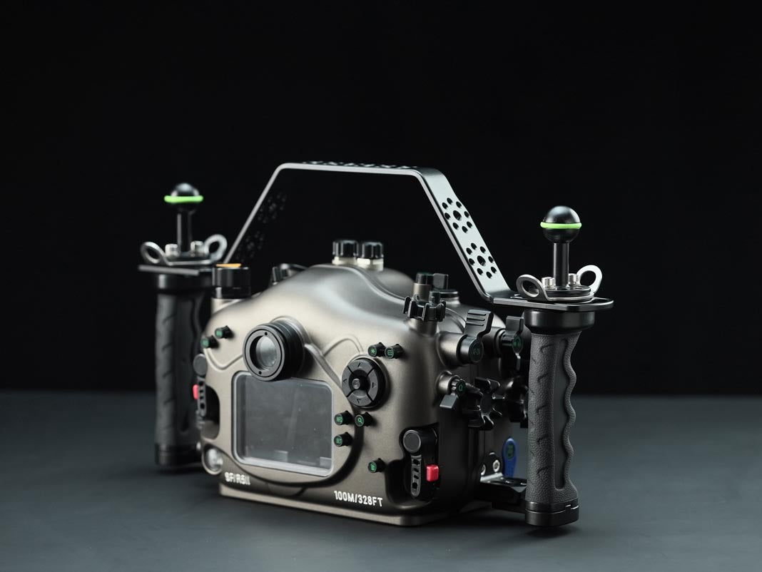 A professional underwater camera housing rig with a matte black metal handle, dual vertical handles, and green-accented side grips, shown on a dark studio background.