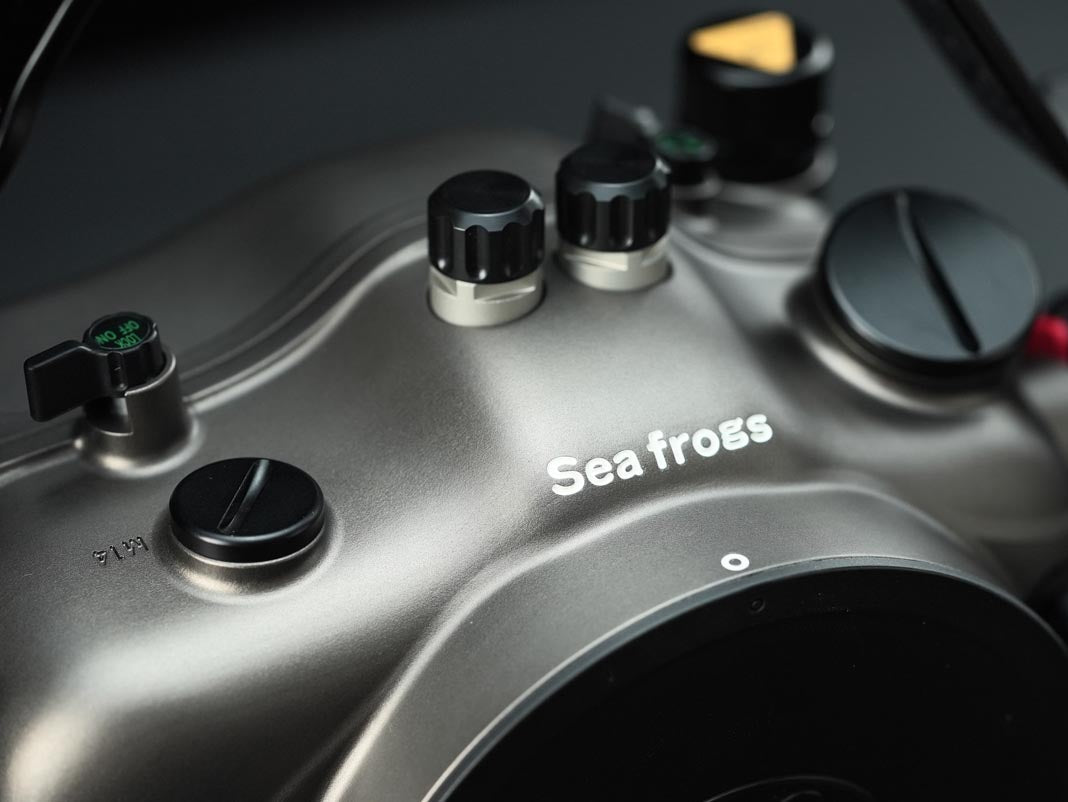 Close-up of a metallic gray Sea FROGS underwater housing with black control knobs and white brand lettering.